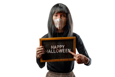 Indonesian southeast asian transgender man dressed as a woman wearing a bloody face mask and showing the text of Happy Halloween on a blackboard. Concept of Halloween, Sister Hong, or red uncleの写真素材