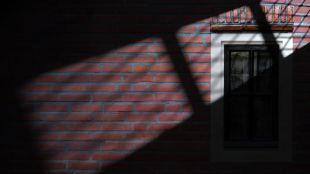 Dramatic shadow of window light casting on the outdoor brick wall texture. Copy space. Textured backgroundの写真素材