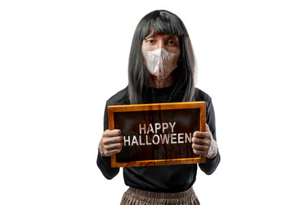 Indonesian southeast asian transgender man dressed as a woman wearing a bloody face mask and showing the text of Happy Halloween on a blackboard. Concept of Halloween, Sister Hong, or red uncleの写真素材