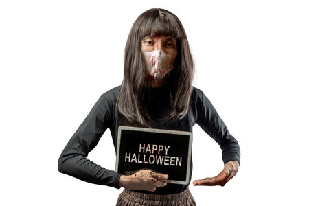 Indonesian southeast asian transgender man dressed as a woman wearing a bloody face mask and showing the text of Happy Halloween on a tablet screen. Concept of Halloween, Sister Hong, or red uncleの写真素材