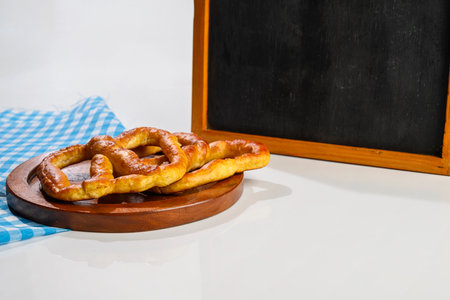 Pretzel loaf with a blackboard and blue checkered tablecloth or napkin on a white table. Copy space.