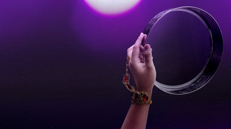 Woman looking at the moon through a sieve or strainer for the Karwa Chauth festival celebration....