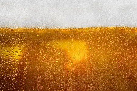Closeup view of refreshing golden beer with foam in a cold mug. Abstract and textured background....