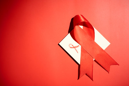 Red ribbon on a red background. Symbolizing awareness and support for HIV or AIDS patients. World Aids Day. Concept of Healthcare and Medicineの写真素材