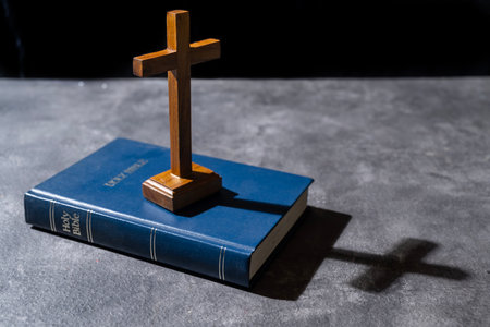 Blue book of the Holy bible and Christian cross. Standing on the table with a dark background. Symbol of faith in God. Concept of Spirituality, Christianity, religion, faith, Jesus, or beliefの写真素材