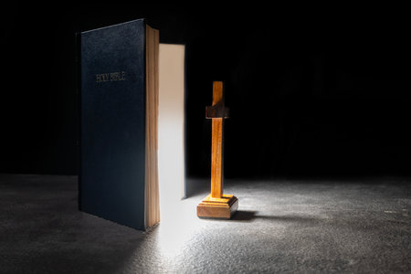 Blue book of the Holy bible and Christian cross. Standing on the table with a dark background. Symbol of faith in God. Concept of Spirituality, Christianity, religion, faith, Jesus, or beliefの写真素材