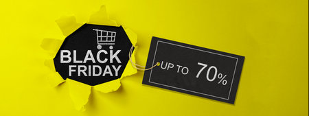 Top view of yellow ripped paper and text of Black Friday with up to 70% text on the label tag. Copy space. Flat lay. Black Friday sale conceptの写真素材