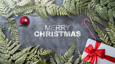Greeting of Merry Christmas text with a giftbox and candy cane on a green leaf frame on a black...