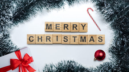 Greeting of Merry Christmas text with a giftbox and candy cane on a Christmas ornament frame on a white background. Holiday greetings or winter themes. Concept of the Merry Christmas celebrationの写真素材