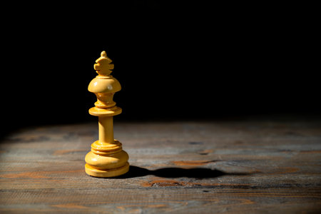 Closeup view of the white chess king standing against a dark background.