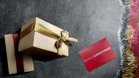 Greeting of Merry Christmas text in a red envelope with a gift box on a black background. Mockup or Copy space. Holiday greetings or winter themes. Concept of the Merry Christmas celebrationの写真素材