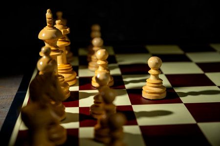 Closeup view of a white chess pawn standing against the opposing pieces on the chessboard. Concept...