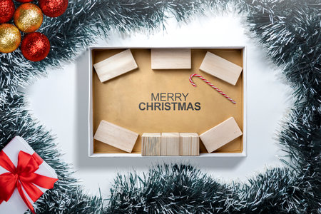 Greeting of Merry Christmas text with a wooden block and a candy cane in a giftbox. Mockup or Copy space. Holiday greetings or winter themes. Concept of the Merry Christmas celebrationの写真素材