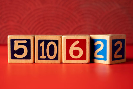 Row of wooden number blocks with various numbers on a red backgroundの写真素材