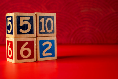 Stack of wooden number blocks with various numbers on a red backgroundの写真素材