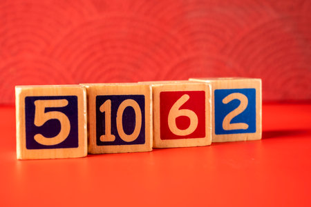 Row of wooden number blocks with various numbers on a red backgroundの写真素材