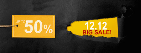 Top view of black ripped paper and text of 12.12 big sale with up to 50% text on the label tag. Copy...