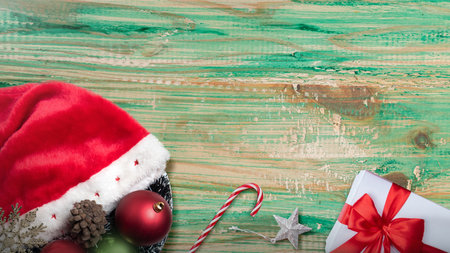 Santa hat, Christmas ornament decoration and gift box on wooden table. Mockup or Copy space. Holiday greetings or winter themes. Concept of the Merry Christmas celebrationの写真素材