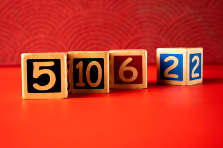 Row of wooden number blocks with various numbers on a red backgroundの写真素材