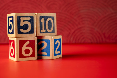 Stack of wooden number blocks with various numbers on a red backgroundの写真素材