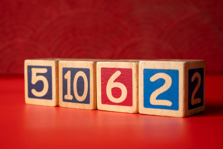 Row of wooden number blocks with various numbers on a red backgroundの写真素材