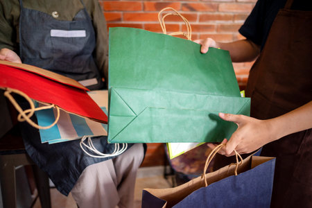 Indonesian southeast asian muslim woman and a man in an apron holding a striped shopping bag inside...