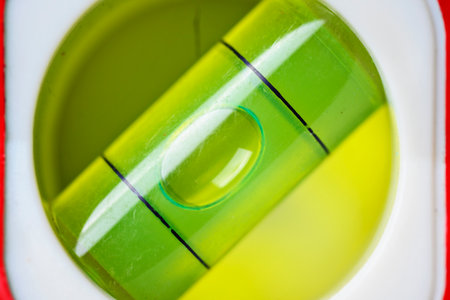 A macro view of a green spirit level vial. The air bubble is perfectly centered between the black marks, indicating a level surface for construction and DIY projectsの写真素材