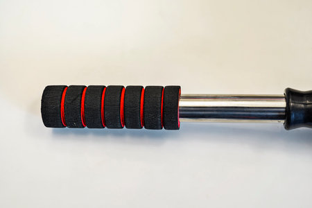 A close up view of a gray microfiber car duster featuring an ergonomic black and red foam handle,...