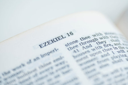 A selective focus macro shot of an open Bible page featuring the chapter title Ezekiel 16, showing...