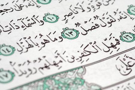 Detailed macro view of the Holy Quran featuring Arabic calligraphy and verse markers. The image...