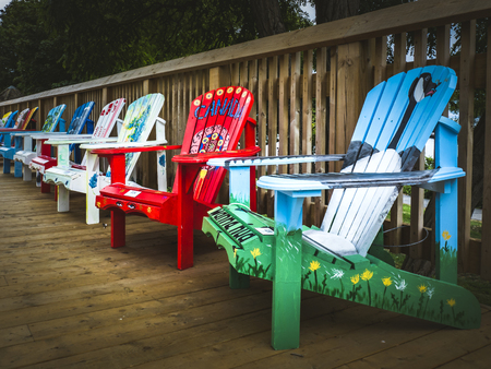 Colorful Muskoka chairs with colorful designs on the sidewalk of Bronte Village.のeditorial素材