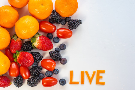 Colorful fruits arrangement in a white background with the word Live made out of tangarine peels.の写真素材