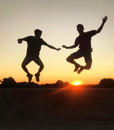 True friendship jumping together with a feeling of freedom and companionship during sunsetの写真素材