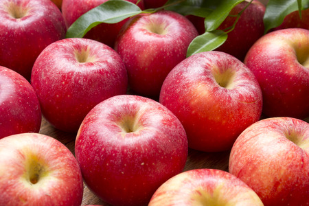 Many red apples with leaves on a wooden background. Nature fruit concepの写真素材