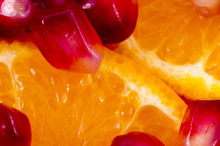 Macro peeled ripe pomegranate fruit with many slices of orange fruit for backgroundの写真素材
