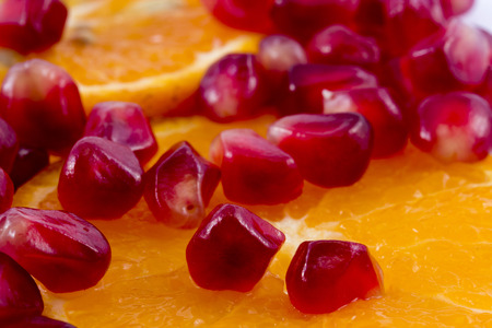 Macro peeled ripe pomegranate fruit with many slices of orange fruit for backgroundの写真素材