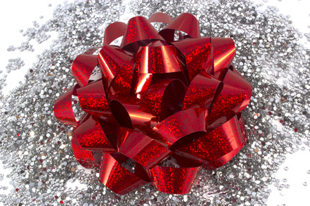 Red holiday gift bow on white background with silver glitterの写真素材
