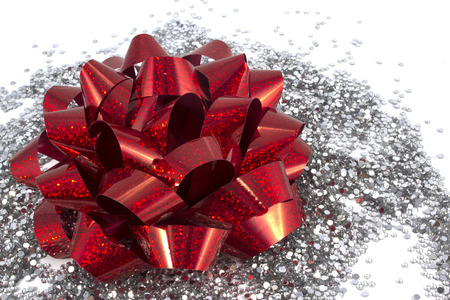 Red holiday gift bow on white background with silver glitterの写真素材