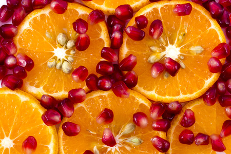 Macro peeled ripe pomegranate fruit with many slices of orange fruit for backgroundの写真素材