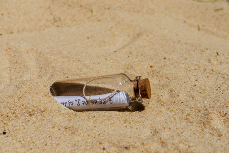 Glass bottle with a rolled-up message revealing coordinates, lying on the sand, suggesting a hidden...