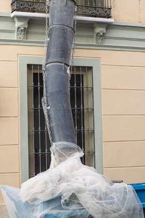 Waste chute funneling construction and demolition debris into a skip, facilitating efficient refuse removal at a building renovation siteの写真素材