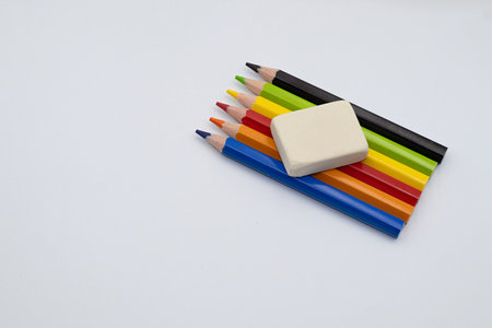 Art supplies, including colored pencils and an eraser, arranged on a clean white surface, representing creativity and educationの写真素材