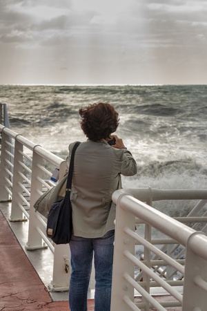 woman on a suspsion bridge in front a big storm in massa , tuscany italyの写真素材