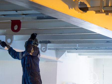 Seaman ship crew working on deck painting the at aft maneuvering stationの写真素材