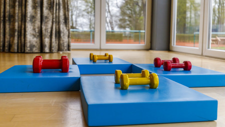 yellow, red, small dumbbells for aerobics and yoga on a blue matの写真素材
