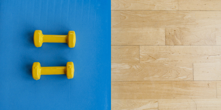 yellow little dumbbells for aerobic and yoga exercises on a blue matの写真素材