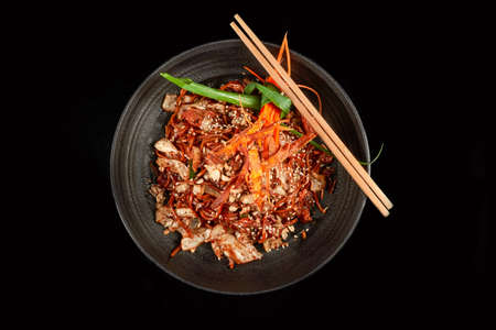 Noodles in a Black Bowl with Cashew Cabbage Fried Onions Sesame and Carrots with Chopsticks Side...
