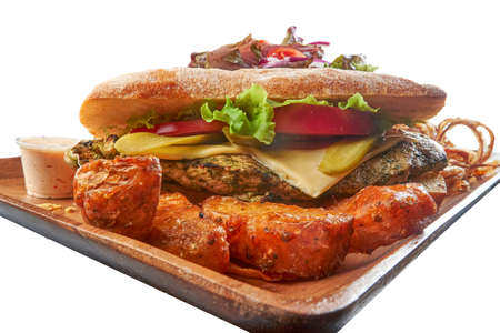 Grilled Chimichurri Chicken Ciabatta Sandwich with Lettuce Cheese and Tomato on Wood Plate With Potato Wedges and a Salad Bowl with Mayonnaise Spicy Sauce and Fried Onionsの写真素材
