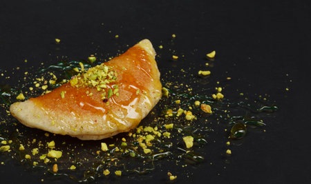 Qatayef, Traditional Arabic Ramadan Sweets with pistachio and honey on black background,side viewの写真素材