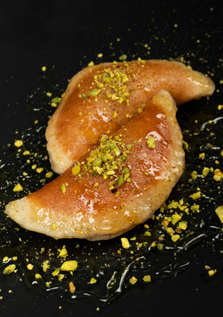 Qatayef, Traditional Arabic Ramadan Sweets with pistachio and honey on black background,top viewの写真素材